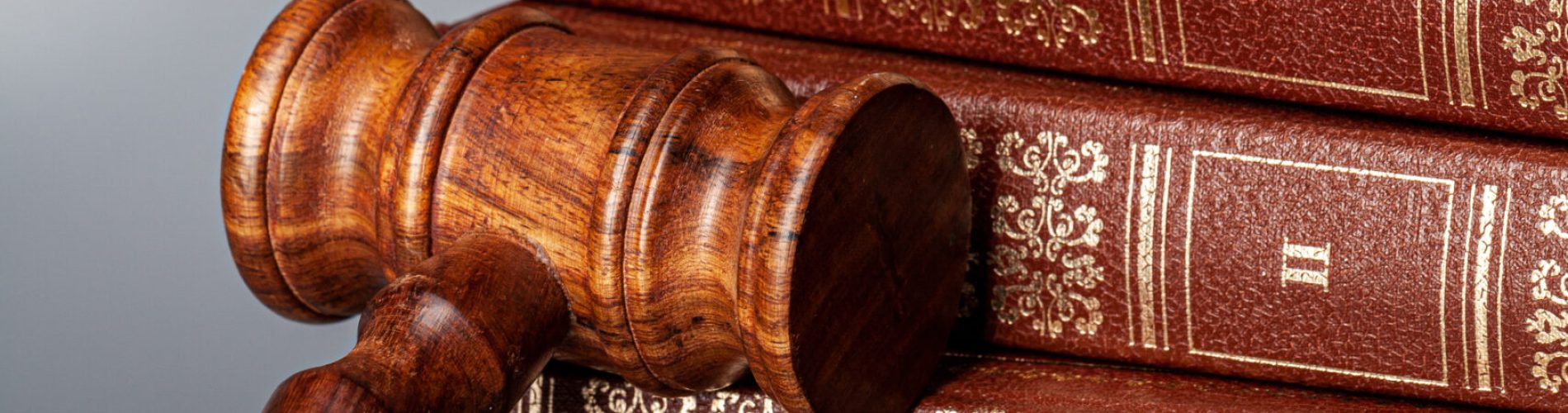 Brown wooden gavel with stack of books on gray table
